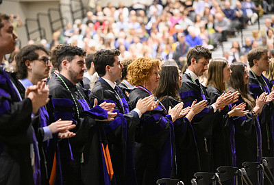 Group of graduates in caps and gowns in an auditorium.