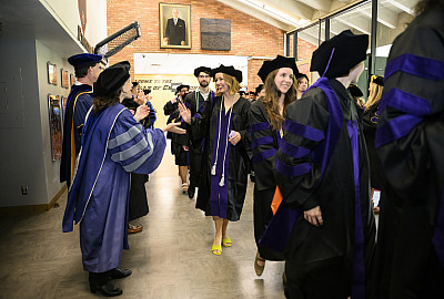 Graduates walking in a line inside an auditorium.
